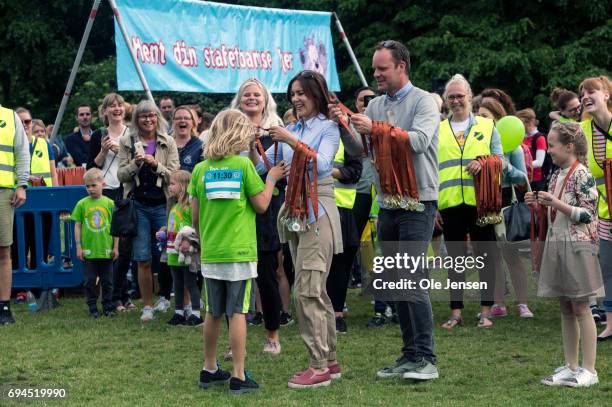 Crown Princess Mary of Denmark presents medal to the first runner passing the finishing line at the 'Children's Relay Run' in Faelledparken on June...