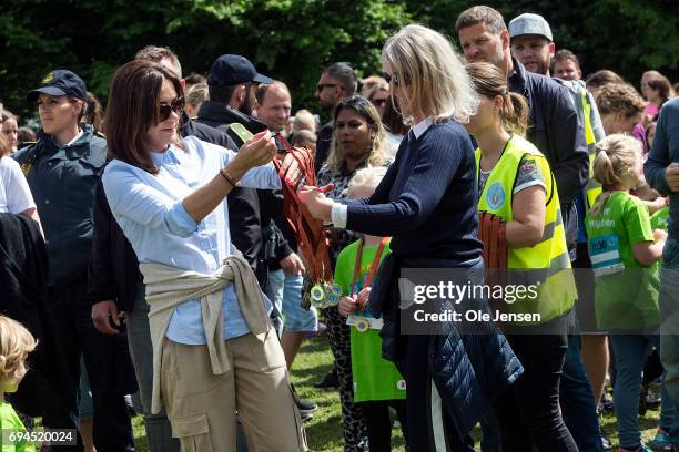 Crown Princess Mary of Denmark presents medal to a young runner having passed the finishing line at the 'Children's Relay Run' in Faelledparken on...
