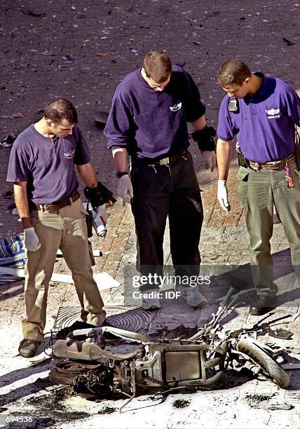 Israeli police investigators inspect the remains of a motor scooter at the scene of a suicide bombing January 25, 2002 in Tel Aviv. A Palestinian...