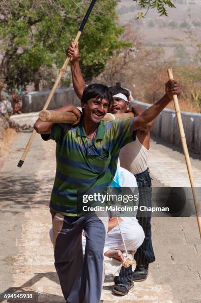 mount shatrunjaya, 'doolie' workers carry a jain pilgrim at holy site at palitana, gujarat - palitana stock pictures, royalty-free photos & images