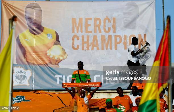 Ivory Coast's supporters cheer under a poster of late football player Cheick Tiote at the stade de la paix in Bouake on June 10, 2017 during 2019...