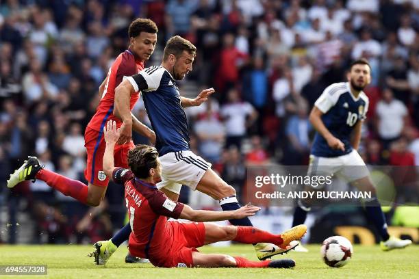 England's midfielder Adam Lallana slides in to tackle Scotland's midfielder James McArthur during the group F World Cup qualifying football match...