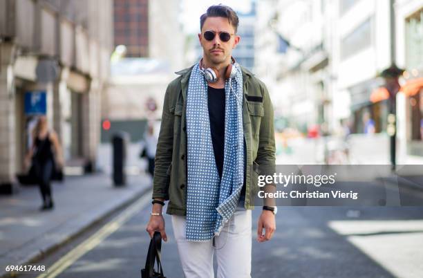 Guest wearing white pants, military jacket, blue scarf, hand bag during the London Fashion Week Men's June 2017 collections on June 10, 2017 in...