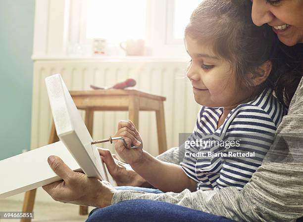 mother helping daughter building furniture - bjarte rettedal stock-fotos und bilder