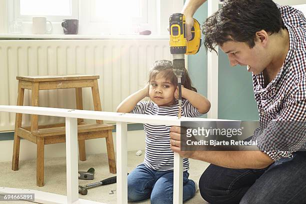 daughter covering ears while father uses drill - bjarte rettedal stock pictures, royalty-free photos & images