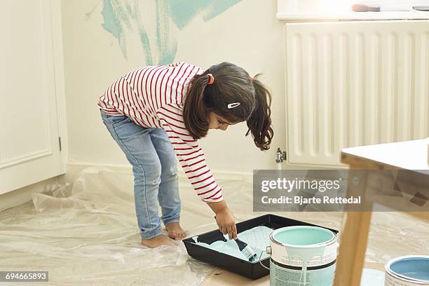 girl dipping paint brush in tray - bjarte rettedal stock pictures, royalty-free photos & images