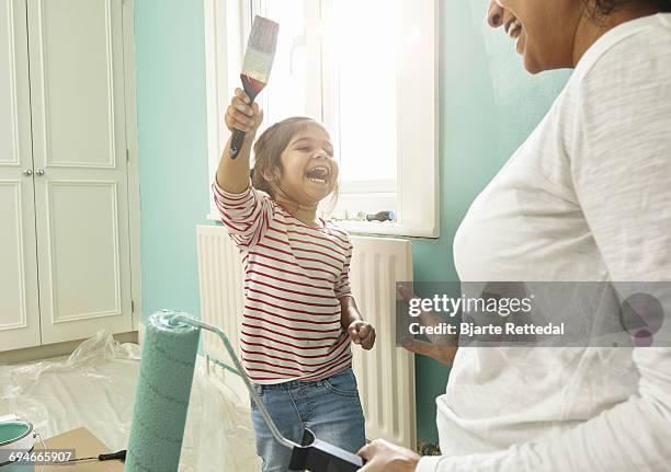 mother and daughter playing while decorating room - bjarte rettedal stock-fotos und bilder