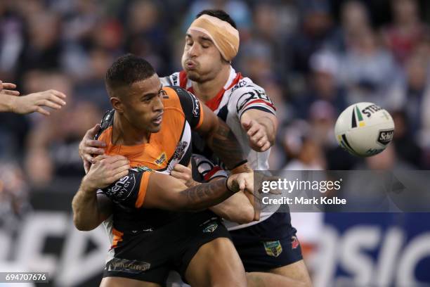 Michael Chee-Kam of the Tigers passes as he is tackled by Ryan Matterson of the Roosters during the round 14 NRL match between between the Wests...