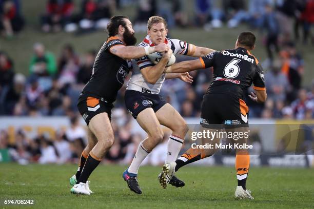 Mitchell Aubusson of the Roosters is tackled by Aaron Woods and Tu'imoala Lolohea of the Tigers during the round 14 NRL match between between the...