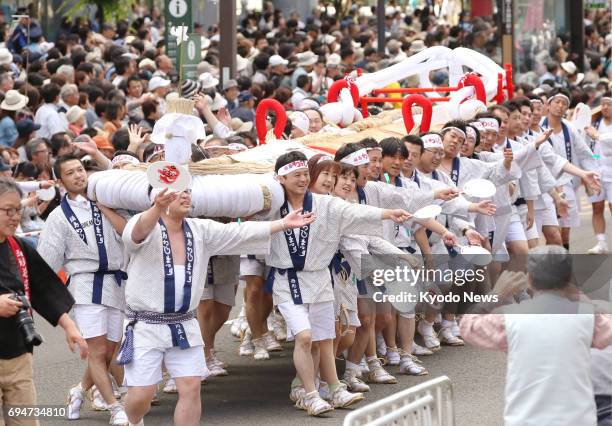 People of the Fukushima Waraji Festival group march through a street in Sendai carrying a gigantic "waraji" straw sandal during the Tohoku Kizuna...