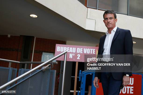 Former French Socialist Prime Minister Manuel Valls leaves after casting his vote during the first round of the legislative elections in Evry, south...