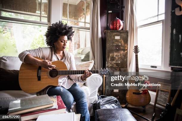 woman playing guitar at home - guitarra fotografías e imágenes de stock