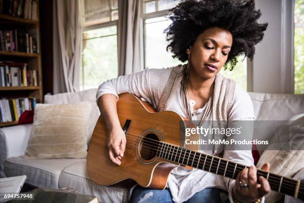woman playing guitar at home - akustikgitarre stock-fotos und bilder