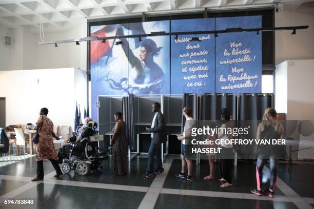 Voters line up to cast their ballots in the first round of the legislative elections, at the City Hall in Evry, suburban Paris on June 11, 2017. /...