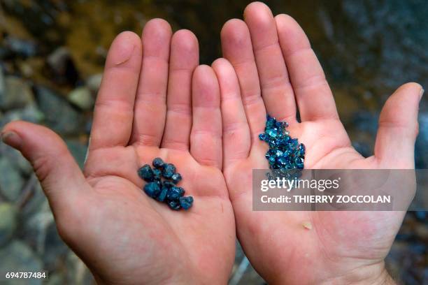 Nicolas Leger, an amateur gemologist, holds cut and raw sapphires in a river in Issoire, on May 27, 2017. / AFP PHOTO / Thierry Zoccolan