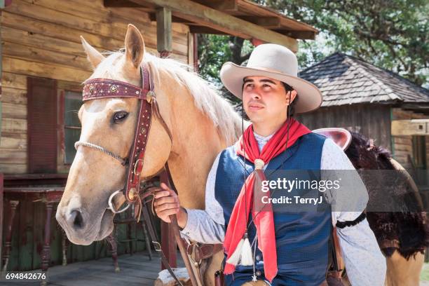 cowboy walks his horse down main street in a western setting - old west town stock pictures, royalty-free photos & images