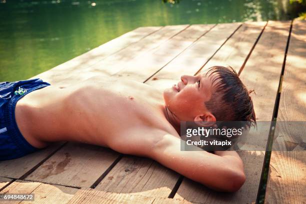 little boy lying down on a wooden deck by the lake - 11 loch stock pictures, royalty-free photos & images