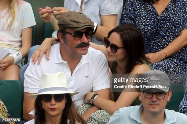 Actor Jean Dujardin and Nathalie Pechalat watches on from Court Philippe Chatrier during the mens singles final match between Rafael Nadal of Spain...