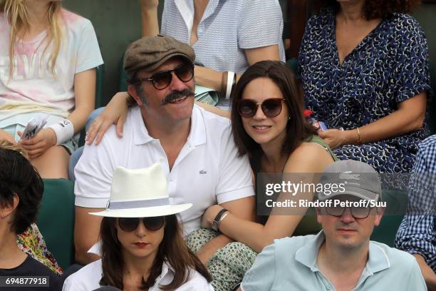 Actor Jean Dujardin and Nathalie Pechalat watches on from Court Philippe Chatrier during the mens singles final match between Rafael Nadal of Spain...