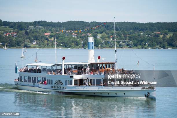 An excursion boat packed with tourists is driving on the Ammersee Lake on June 11, 2017 near Utting, Germany. Summer weather of blue skies and 29...