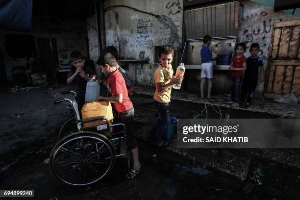 Palestinian children fill jerricans with drinking water from public taps during the Muslim holy month of Ramadan at the Rafah refugee camp, in the...