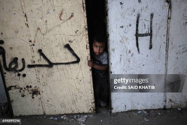 Palestinian boy peers through the door of his house at the Rafah refugee camp, in the southern Gaza Strip, June 11, 2017.