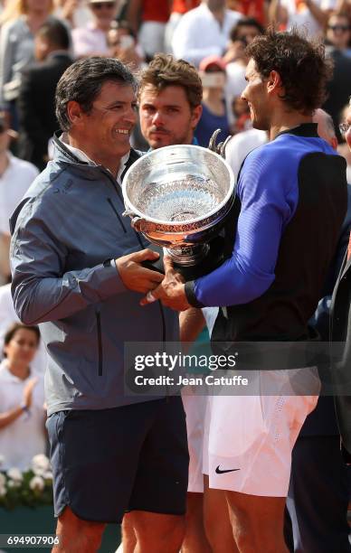 Toni Nadal and winner Rafael Nadal of Spain while finalist Stan Wawrinka of Switzerland looks on during the trophy ceremony following the men's final...