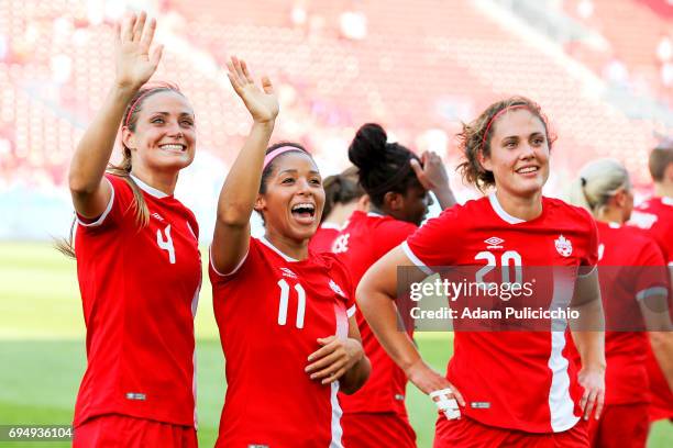 Defender Shelina Zadorsky of Team Canada and teammates Midfielder Desiree Scott, and Defender Shannon Woeller smile and wave to the crowd after...