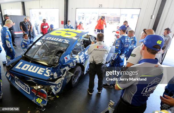 Crew members look over the Lowe's Chevrolet, driven by Jimmie Johnson ,, after it was involved in an on-track incident during the Monster Energy...