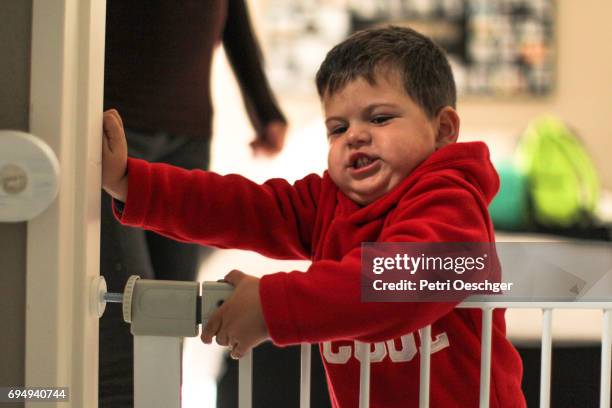 a young boy tries to open a child security gate. - baby gate stock pictures, royalty-free photos & images