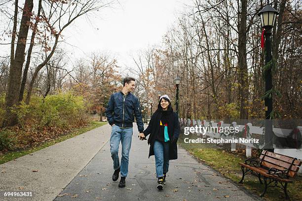 man and woman walking in park holding hands - toledo ohio stockfoto's en -beelden