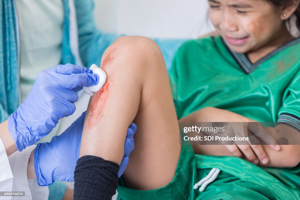 Unrecognizable doctor cleans soccer player's wounded shin
