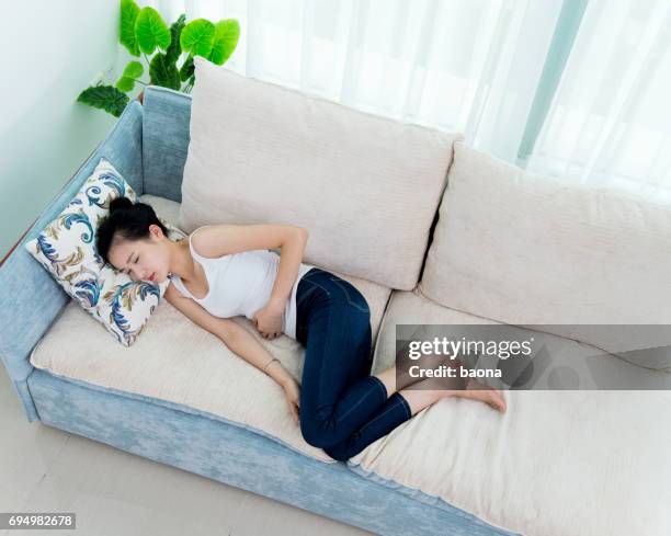 young woman having stomachache on sofa - underweight stock pictures, royalty-free photos & images