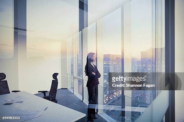businesswoman looking out window in meeting room - three quarter front view ストックフォトと画像