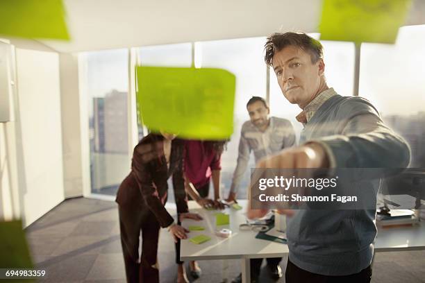 business colleagues reviewing ideas on glass wall - décision photos et images de collection