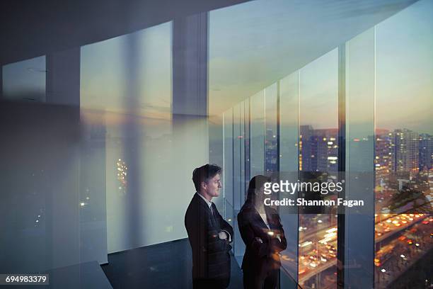 business colleagues looking out window in office - erwartung stock-fotos und bilder