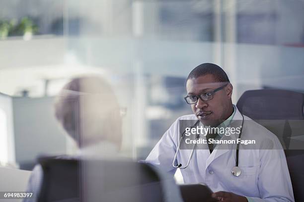 doctor talking with patient at desk in office - adult patient with doctor and stethoscope foto e immagini stock