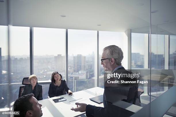 businessman talking with colleagues in meeting - grey hair stock pictures, royalty-free photos & images