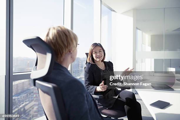 business women talking together in meeting room - two women talking stock pictures, royalty-free photos & images