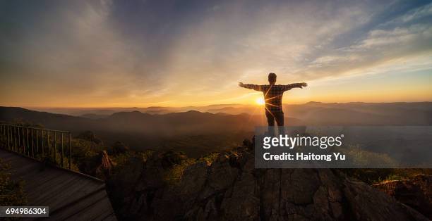 man facing sunset with arm stretched - young man asian silhouette stock pictures, royalty-free photos & images