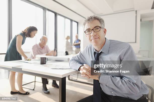 portrait of man in meeting room with colleagues - teal portrait stockfoto's en -beelden