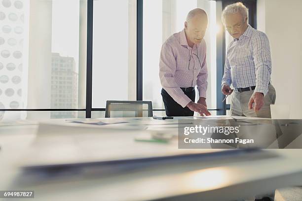 men discussing layouts on table in office studio - architekt mit plan frontal stock-fotos und bilder