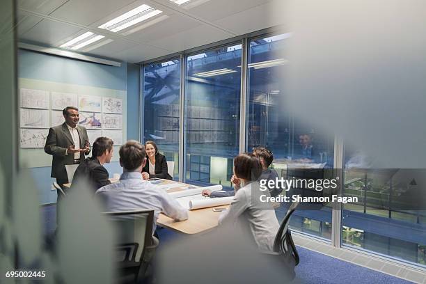 colleagues talking in design office meeting room - multi ethnic business people having discussion at table in board room stock pictures, royalty-free photos & images
