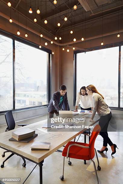 colleagues looking at laptop in design studio - innovation illustration stock pictures, royalty-free photos & images