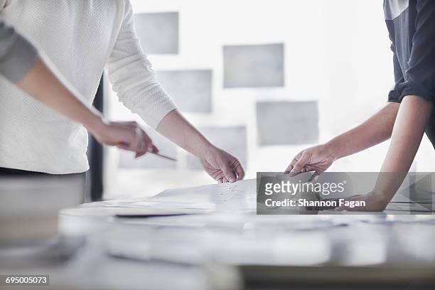 hands on diagram layouts on table in design studio - plano documento fotografías e imágenes de stock