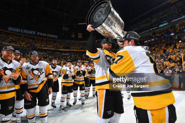 Captain Sidney Crosby of the Pittsburgh Penguins gives the Stanley Cup to teammate Ron Hainsey after Game Six of the 2017 NHL Stanley Cup Final at...