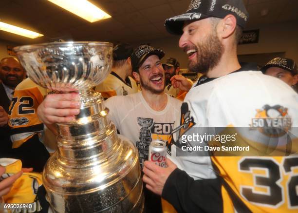 Captain Sidney Crosby and Mark Streit of the Pittsburgh Penguins laugh as they stand with the Stanley Cup in the locker room after Game Six of the...