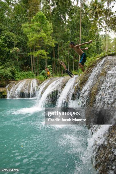 boys jumping from waterfall, cambugahay falls, siquijor. - siquijor islands stock pictures, royalty-free photos & images