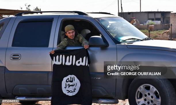 Member of the Syrian pro-government forces holds an Islamic State group flag after they entered the village of Dibsiafnan on the western outskirts of...