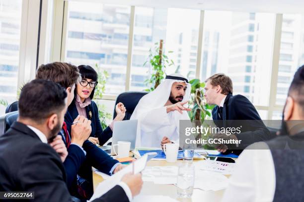 arab businessman whispering key points during a meeting to his colleague - qatar people stock pictures, royalty-free photos & images